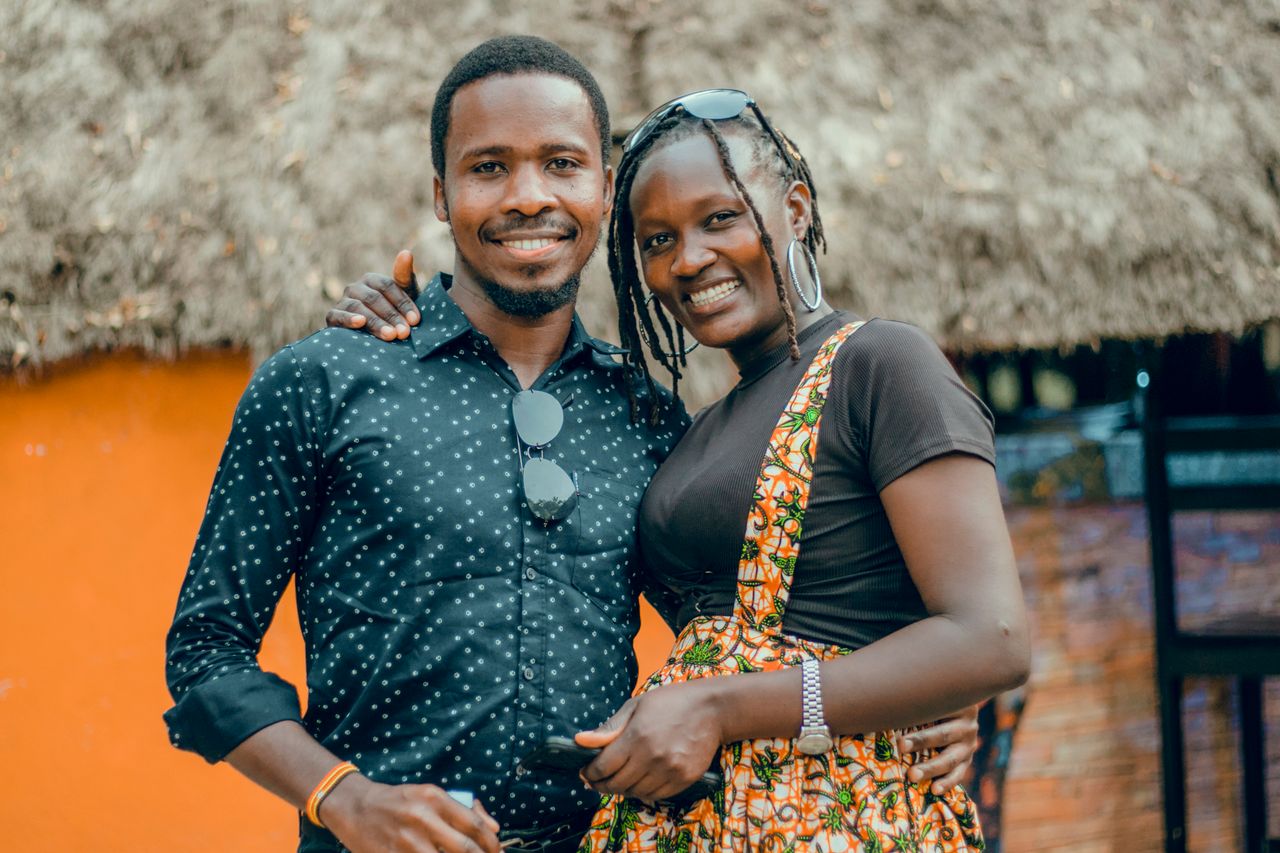 A joyful couple embracing outdoors in Kampala, showcasing vibrant fashion and a warm atmosphere.